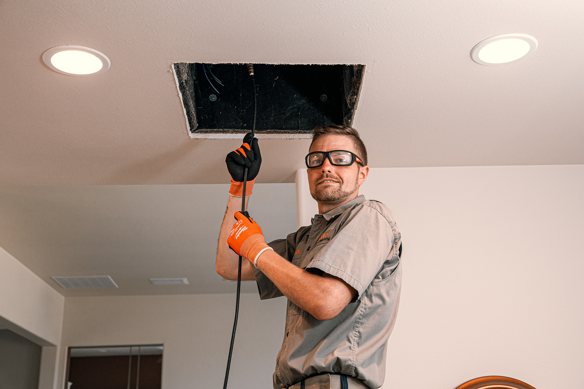 Smiling air duct cleaning service professional cleaning a clients air duct with a hose in Bellevue Washington