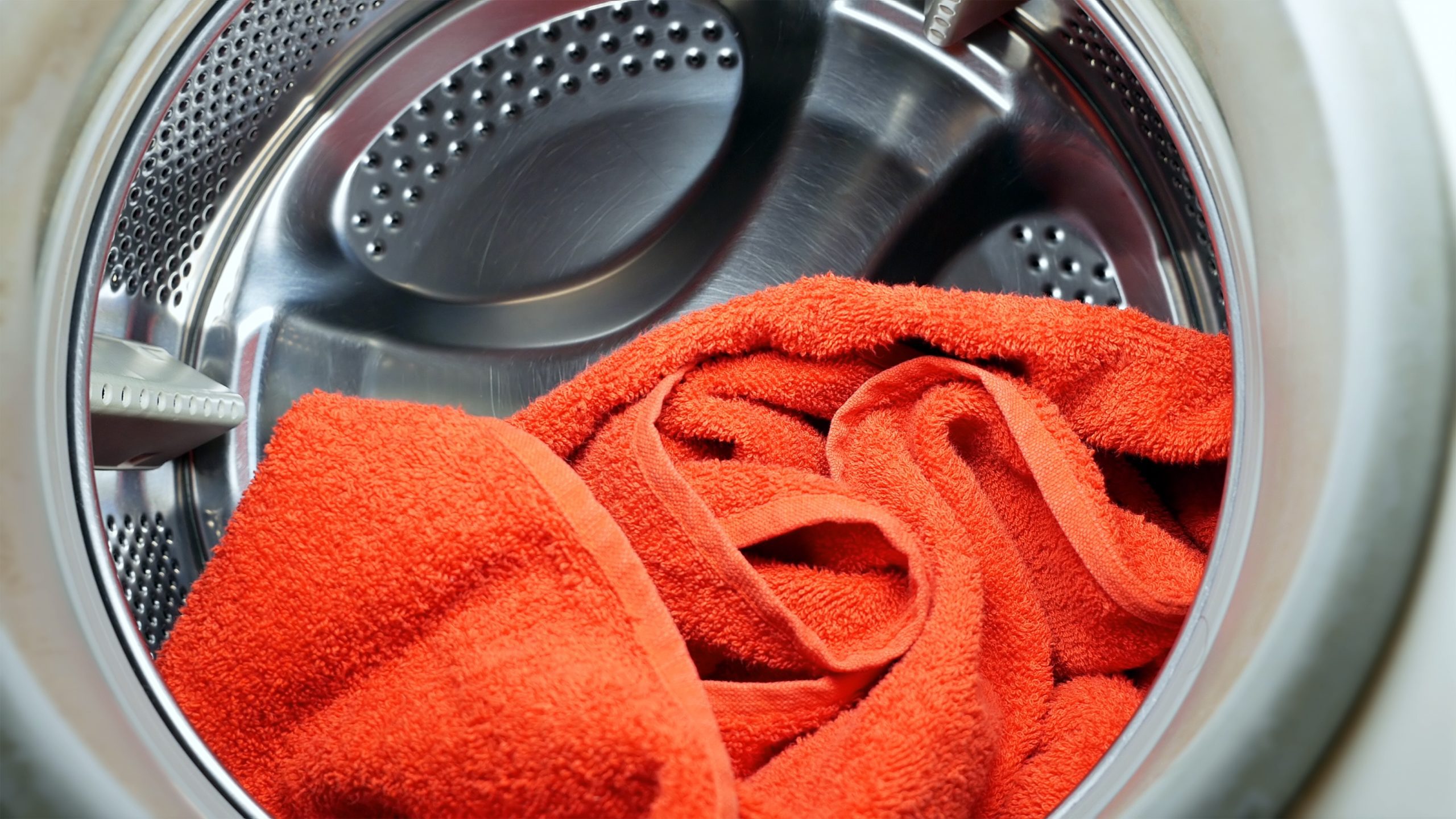Washing or drying machine with red towel in a laundry. Household equipment and cleanliness hygiene housework concept.