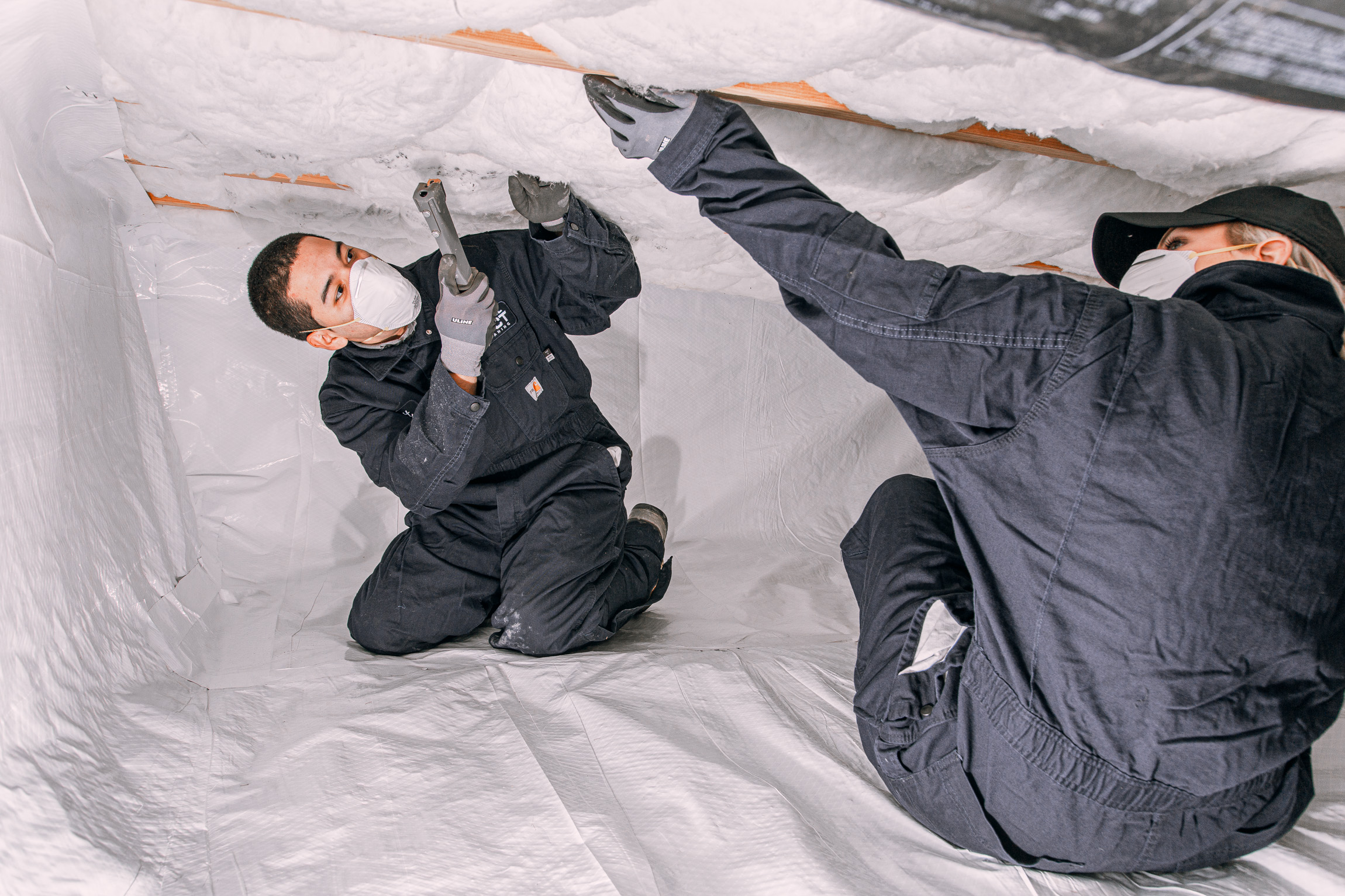 Two professional air duct cleaners walk through the front door of a client's home.