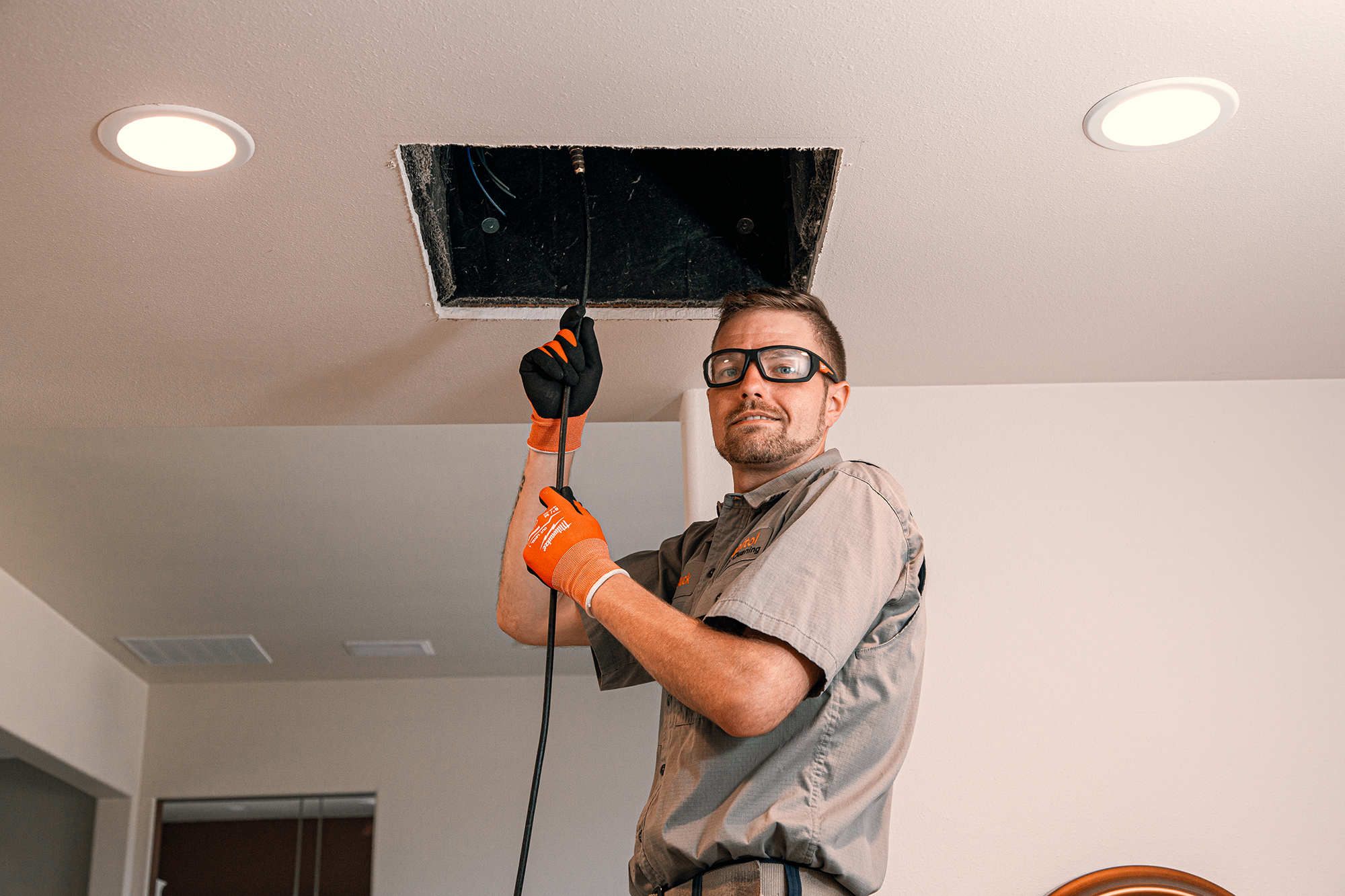 Smiling air duct cleaning service professional cleaning a clients air duct with a hose in Tacoma, Washington