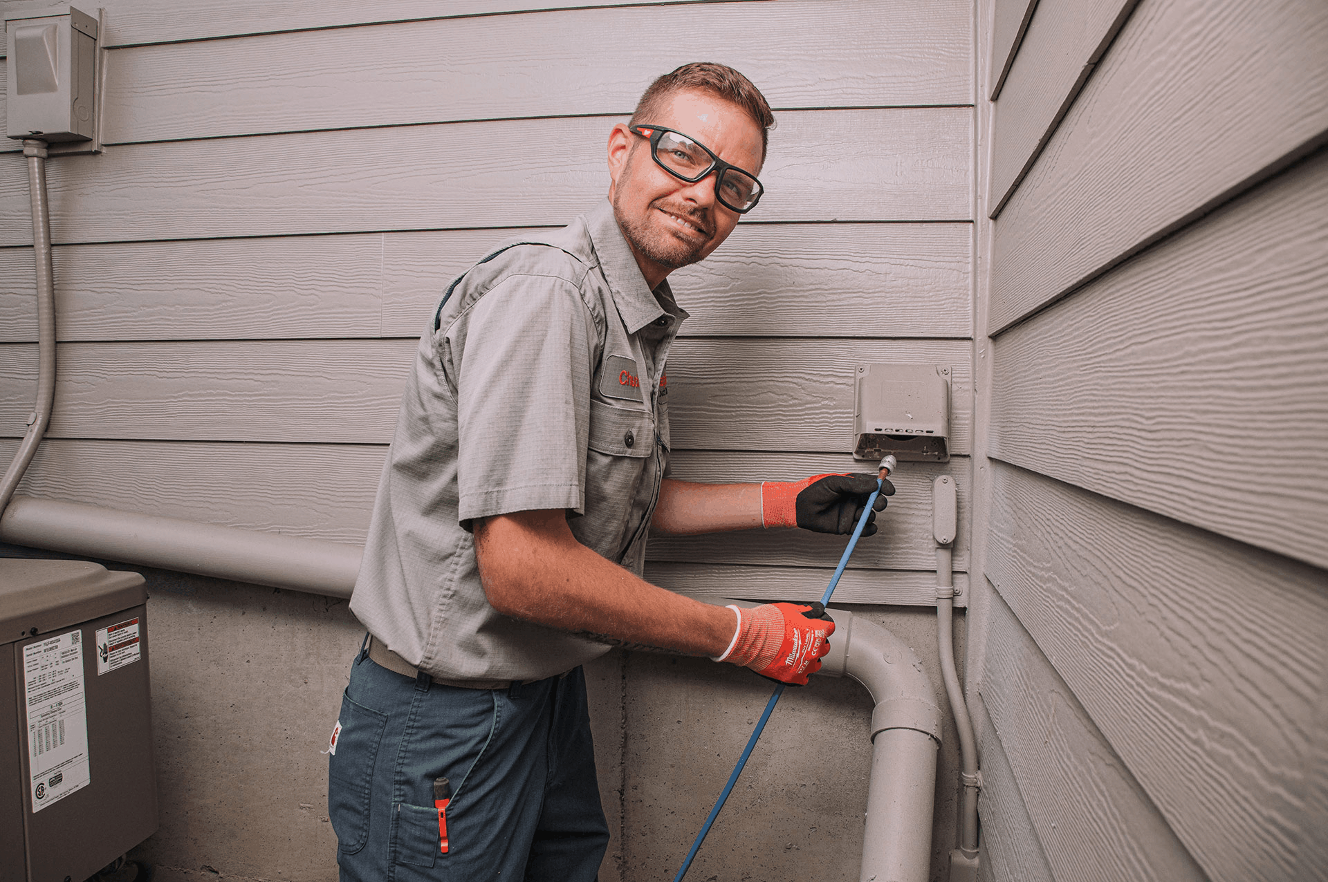 Technician wearing safety glasses and gloves performing an inspection on an outdoor dryer vent in Graham, WA.