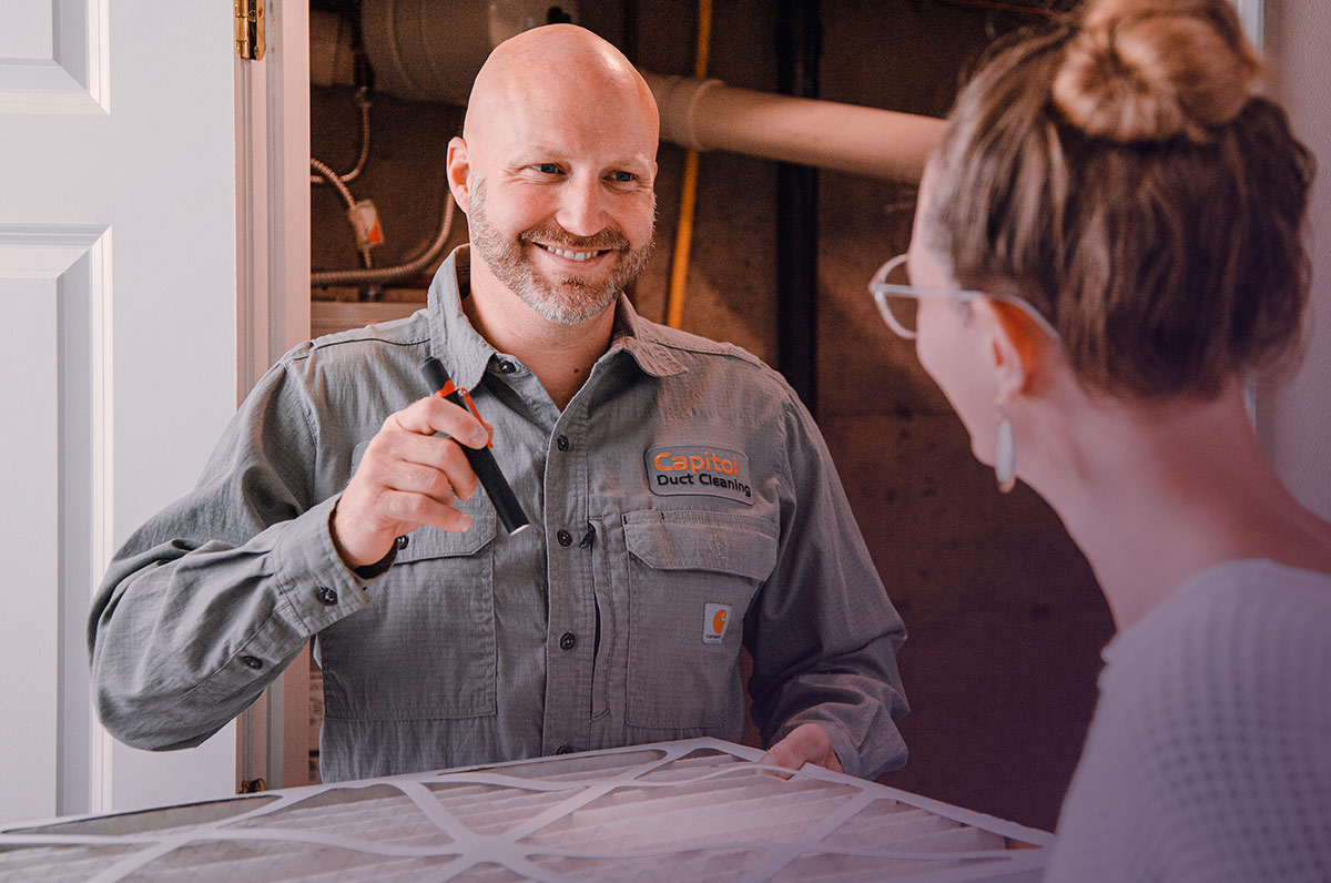 Air duct cleaning provider smiling as they explain their service options with a client in Tacoma, WA.